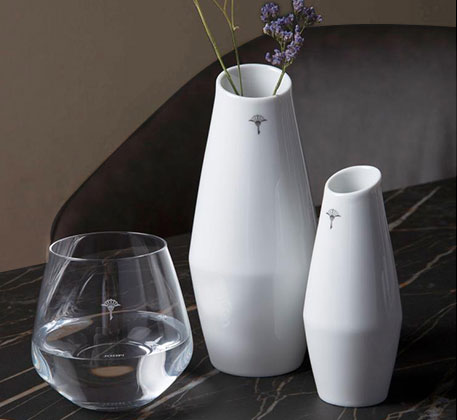 Wasserglas, kleine und große weiße Vase auf schwarzem Marmortisch 