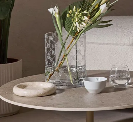Glasvase mit Cornflower-Muster, Blumen, weiße Schalen, Wasserglas mit Cornflower-Muster auf beigem Tisch