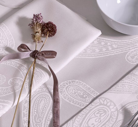 cremefarbige Tischdecke und Serviette, weiße Schale und Strohblumen