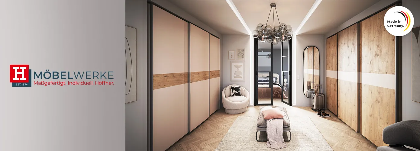 Möbelwerke. Maßgefertigt. Individuell. Höffner. Ankleidezimmer mit 2 Schwebetürenschränken mit 3 Türen, einer in Creme mit Bauchbinde in Holzoptik, der andere in Holzoptik mit Bauchbinde in Creme, Bank, Sessel und Deko. Made in Germany-Siegel.