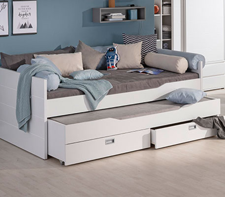 Weißes Kinderbett mit Unterbett samt 2 Schubladen, Kissen, Decke und Deko in einem Kinderzimmer