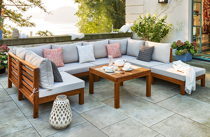 Garten-Loungemöbel in dunklem Holzton und cremefarbenen Auflagen