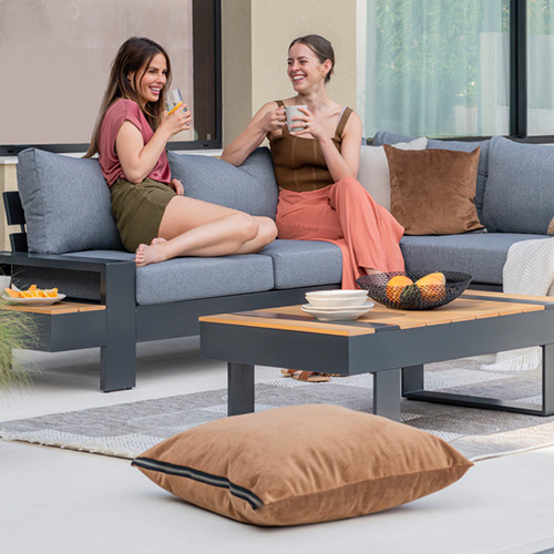 Zwei Frauen sitzen auf einem Garten-Loungesofa