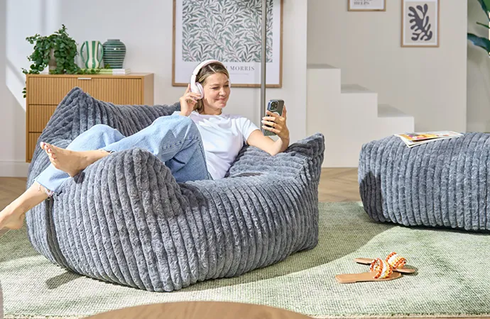 Frau sitzt auf grauem Boneless Sofa, hier geht es zur Markenseite