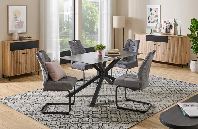 Esszimmer mit schwarzem Tisch, grauen Polsterstühlen und Holzmöbeln mit grauen Akzenten, Deko