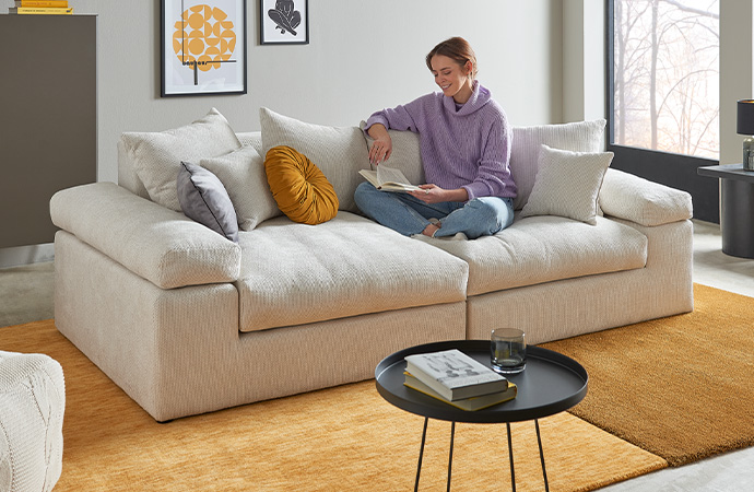 Frau sitzt auf Sofa und liest ein Buch
