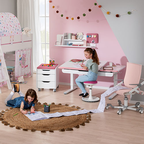 Kinderzimmer mit einem Kind am Schreibtisch und einem Kind, das am Boden ein Heft ausfüllt