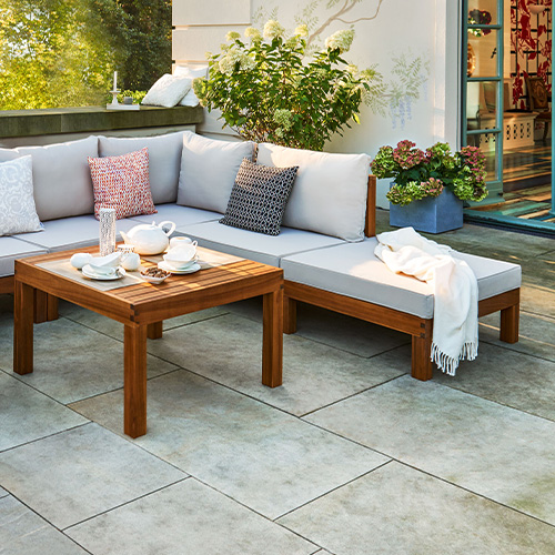 Terrasse mit Outdoor-Lounge-Sitzecke, Holzgestell in warmem Braunton, Sitzkissen in Creme