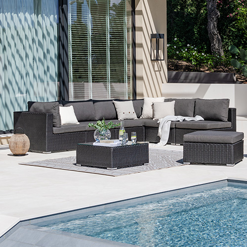 Lounge-Ecke aus dunkelgrauen Polyrattan-Möbeln mit dunkelgrauen Sitzpolstern auf Terrasse 