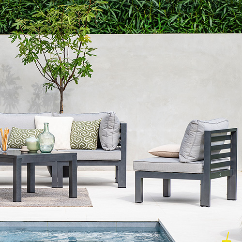 Steinterrasse im Grünen, Gartenloungemöbel in Dunkelgrau mit hellgrauen Polstern, Gartensofa, 1 Sessel, 1 Tisch