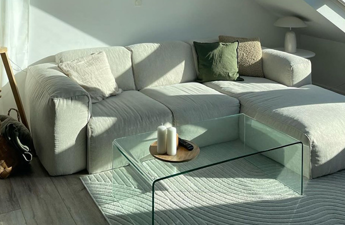Helles Big-Sofa mit Glastisch davor in Dachgeschoss-Wohnzimmer