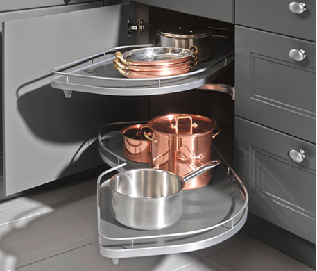 Geöffneter Eckschrank in einer Küche. Aus der geöffneten Tür kommen die ausfahrbaren Tablare mit Töpfen.