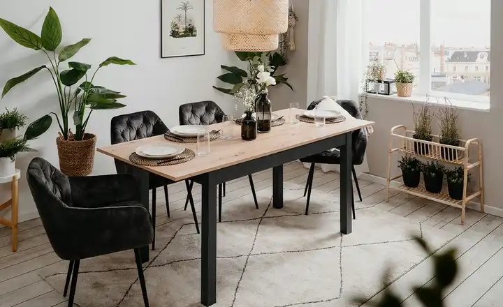 Vier dunkle Stühle mit gesteppter Lehne und schwarzem Gestell an einem schwarzen Tisch mit heller Massivholzplatte