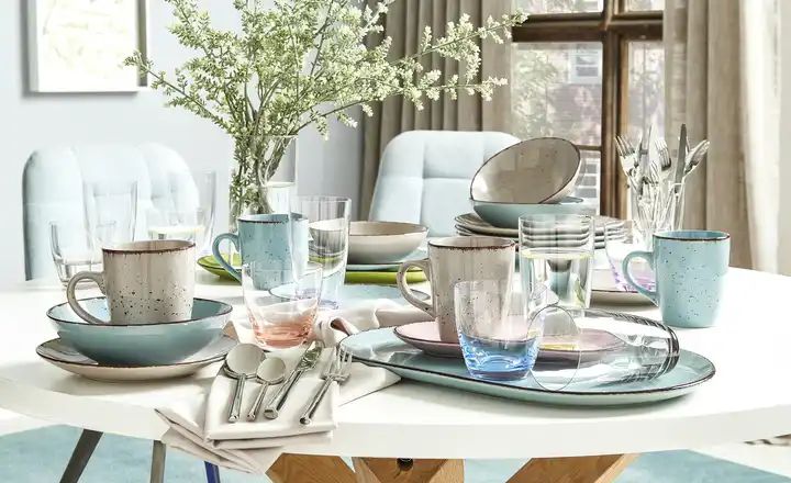 gedeckter weißer Tisch mit hellblauem und grauen Geschirr