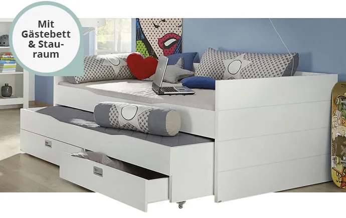 Weiße Bettkombination mit Gästebett & Stauraum in einem Kinderzimmer, Kissen, Deko und Laptop