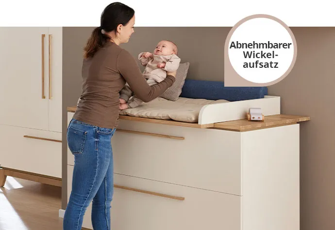 Mutter und Baby an Wickelkommode in Cashmere und Eiche, Hinweis, dass der Wickelaufsatz abnehmbar ist, im Hintergrund Schrank. Deko und Textilien. 