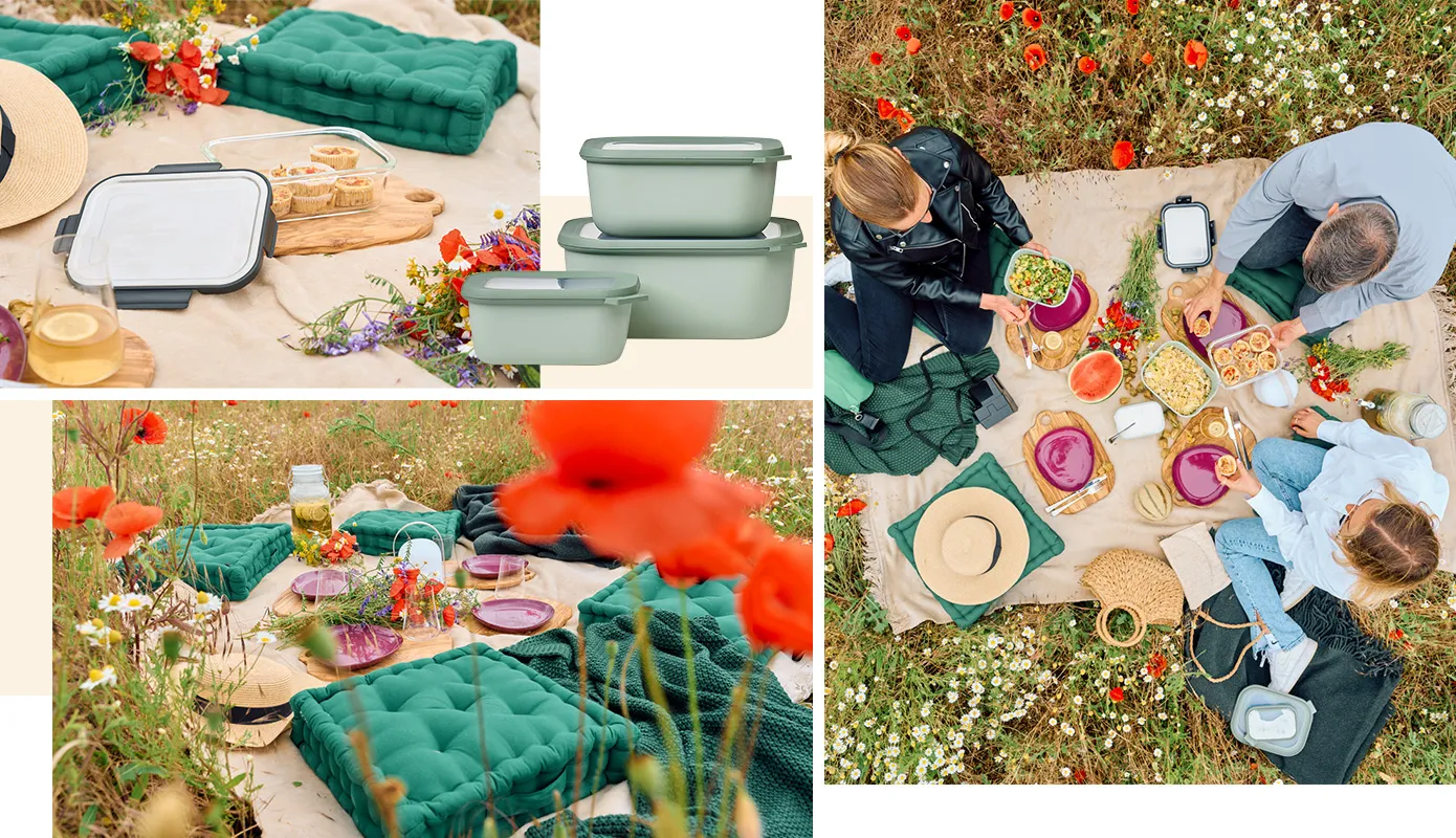 Picknick auf Blumenwiese mit großer beiger Decke und grünen Sitzkissen, Schneidebretter mit lilafarbenen Tellern, LED-Akkuleuchte, Getränkespender, Personen sitzen drumherum mit Fingerfood wie Muffins in Aufbewahrungsdosen