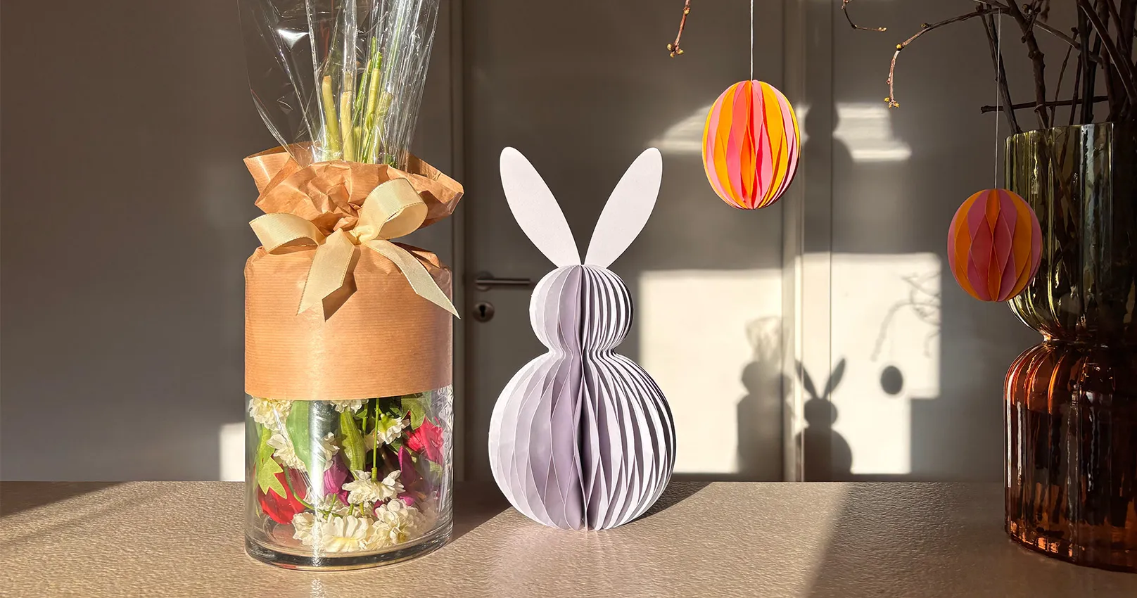 Zylinder-Glasvase mit auf dem Kopf stehendem Blumenstrauss, halb Packpapier umwickelt, Straussende guckt raus