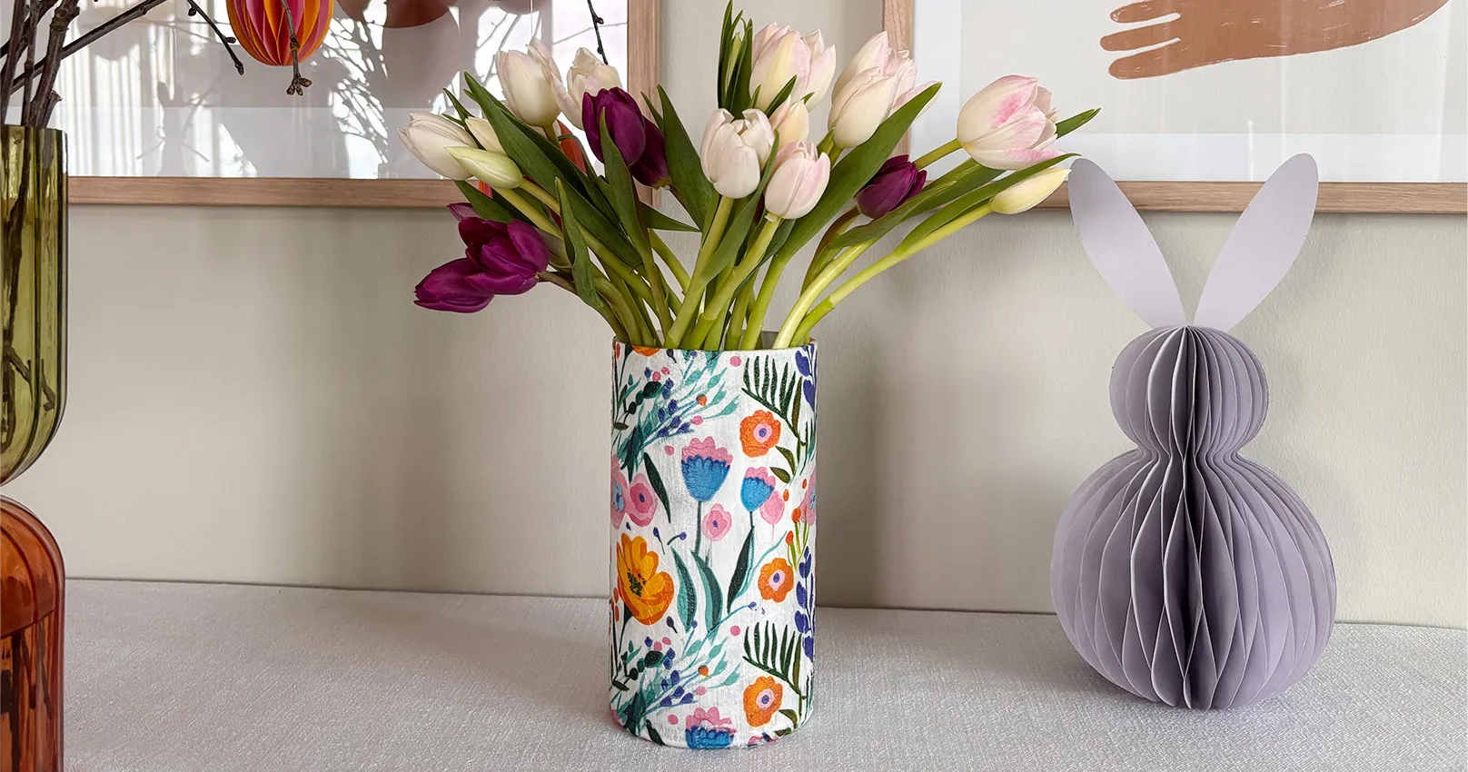 Selbstgemachte Zylindervase blumigem Serviettendruck mit Tulpen und Deko-Papierhase