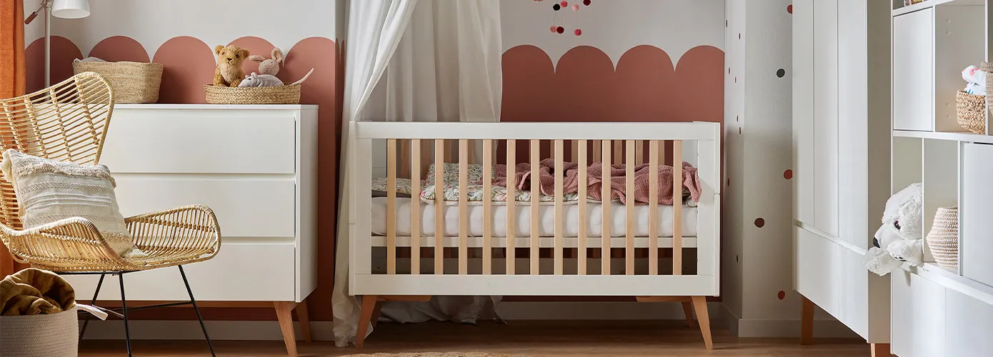 Babyzimmer mit Möbeln im Skandi-Stil in Weiß und hellem Holz. Kommode, Gitterbett, Kleiderschrank und Regal