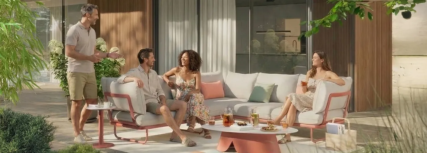 Lounge-Gruppe mit orangenem Gestell und hellen Sitz- und Rückenkissen auf einer Terrasse.