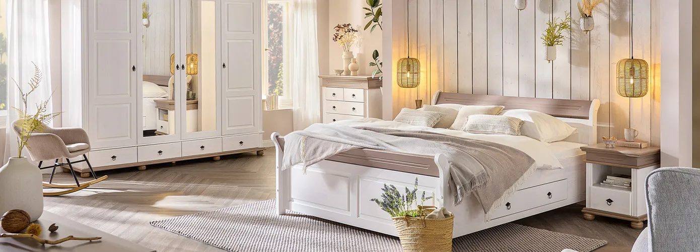 Schlafzimmer mit Landhausmöbeln in Weiß und Holz, weiße und beige Textilien, Rattan-Pendelleuchten, Deko