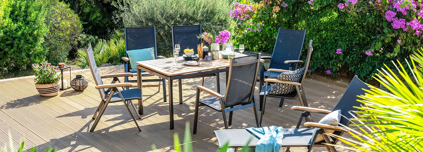 Gartenmöbel in Dunkelgrau und Holz auf sonniger Terrasse. Tisch, 3  Klappstühle, 3 Stapelstühle