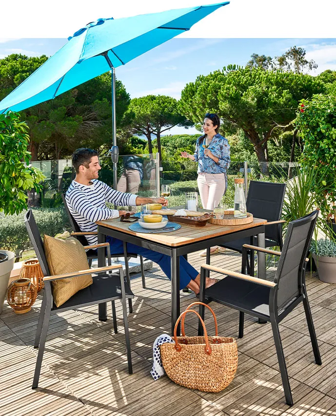 Pärchen auf Holzterrasse im Grünen, Gartenmöbel der Serie - Tisch und 4 Stapelstühle