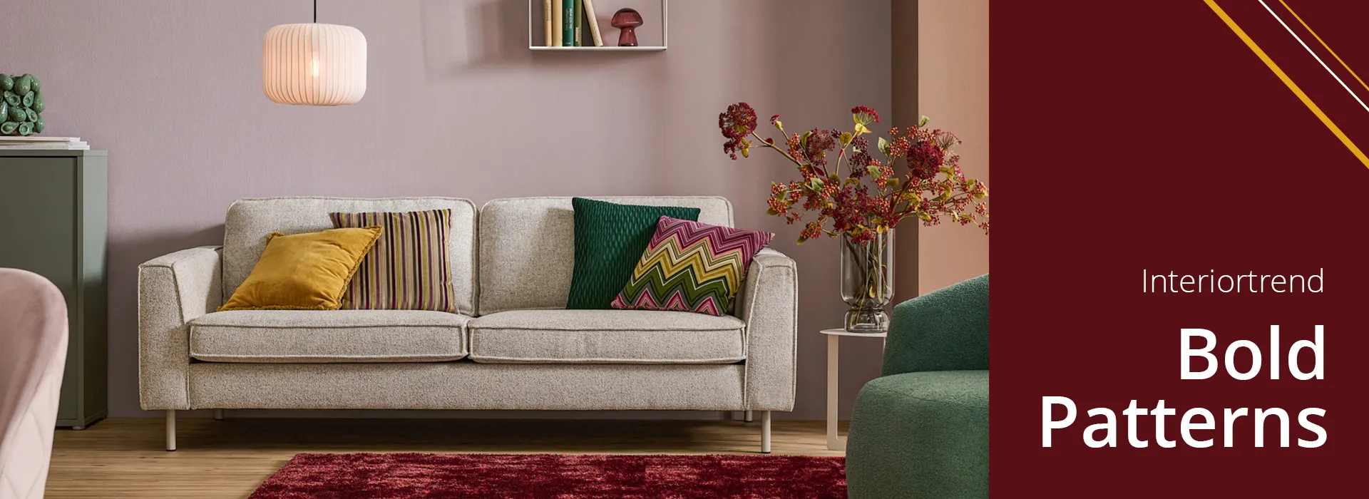 Graues Sofa mit gerzacktem und gestreiften Musterkissen in Grün-Gelb-Rottönen und unifarbenen Kissen in Gelb und Grün